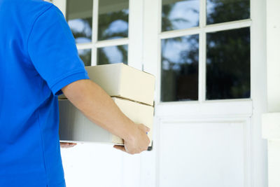 Midsection of man holding boxes while standing at doorway