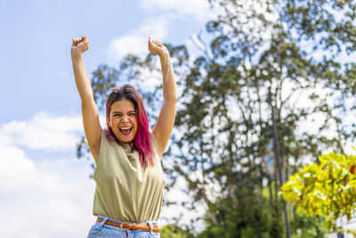 Low angle view of woman with arms raised against sky