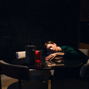 Woman sleeping at table in darkroom