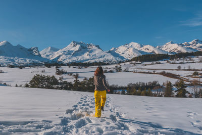 A back view shot of an unrecognizable young woman running towards the french alps mountains