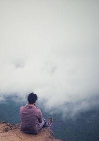 Rear view of man sitting on land