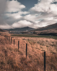 Wooden fence on field against sky