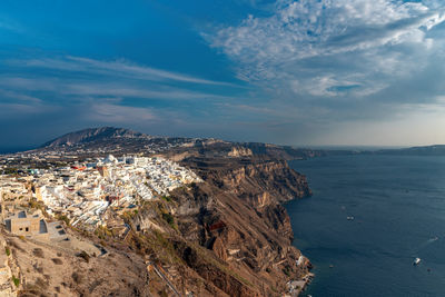 Aerial view of townscape by sea against sky