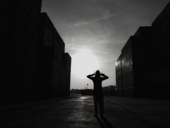Silhouette woman standing by building against sky in city