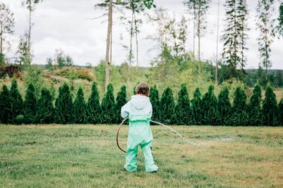 Young girl playing with a hose in the yard in the rain at home