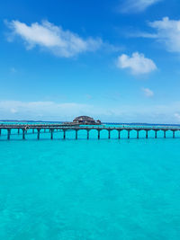 Bridge over sea against blue sky