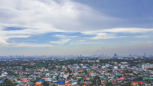 High angle view of city buildings against cloudy sky