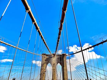 Low angle view of suspension bridge against blue sky