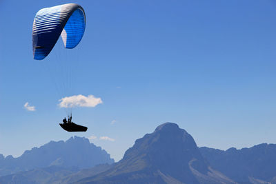 Paraglide flying at dolomites mountains against blue sky