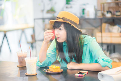 Young woman in drinking glass while sitting on table