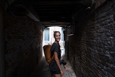 Portrait of smiling woman standing amidst wall