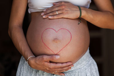 Midsection of woman making heart shape with hands