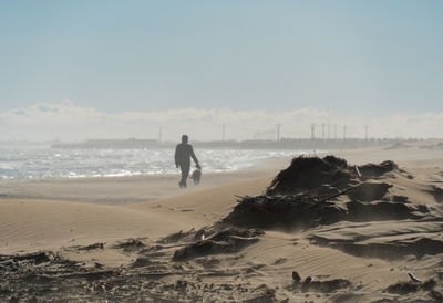 Rear view of man on beach against sky