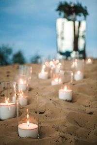 Illuminated tea light candles on sand
