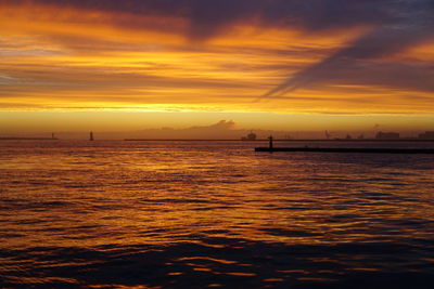 Scenic view of sea against cloudy sky at sunset