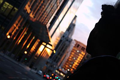 Tilt image of man looking at illuminated buildings in city