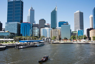 River by skyscrapers in city against sky