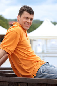 Portrait of smiling boy sitting against sky