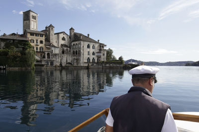 Rear view of man in river against buildings