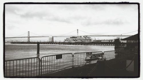 Bridge over river against cloudy sky