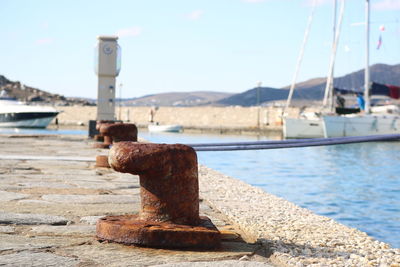 Close-up of rusty pier at harbor against sky