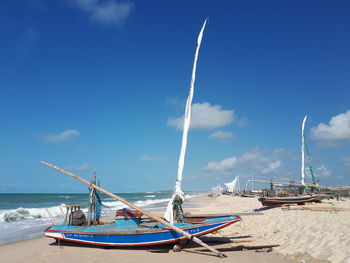 Ship moored on beach against blue sky