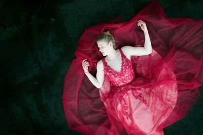 High angle view of woman in red dress lying down on floor