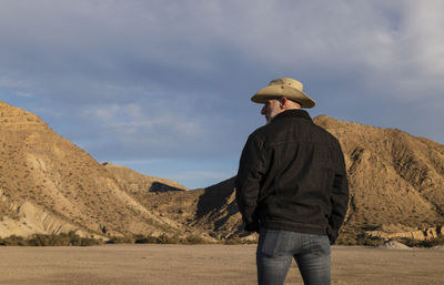 Adult man in cowboy hat standing against mountains in tabernas desert. almeria, spain