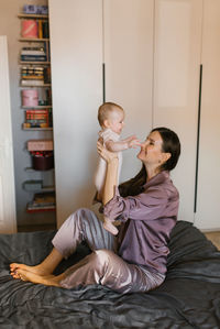 Loving mother plays on the bed with her baby son