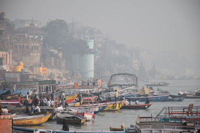 Boats in ganges by buildings in city against sky