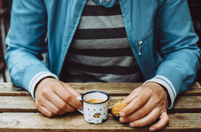 Midsection of person having coffee with food at table