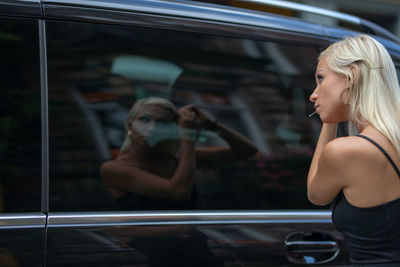 Woman making hair while looking in car window