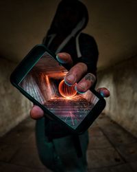 Close-up of man holding smart phone in tunnel