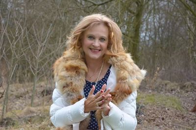 Portrait of smiling senior woman standing in forest