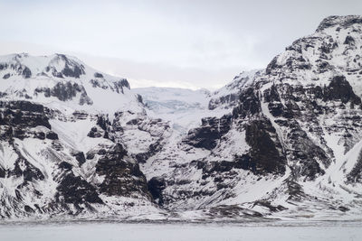 Scenic view of snowcapped mountains by sea against sky