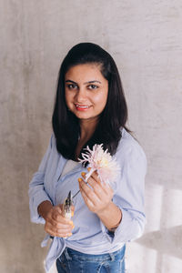 Woman of indian ethnicity holding florist tools and a pastel colored flower