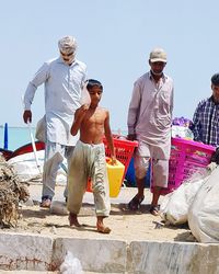 Men standing against clear sky on sunny day