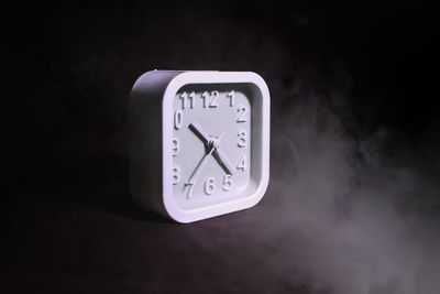 Close-up of clock on table against black background