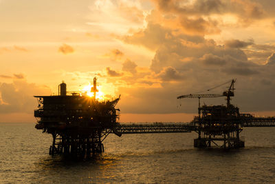 Seascape of golden hour offshore with silhouette of an oil production platform 