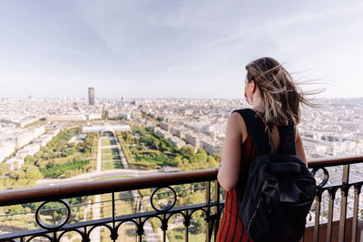 Woman standing by railing against cityscape