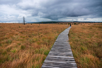 Boardwalk on field against sky