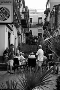 People sitting on street against buildings in city