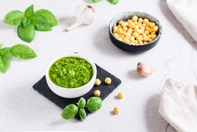 Homemade pesto sauce in a bowl and ingredients on the table. healthy italian cuisine