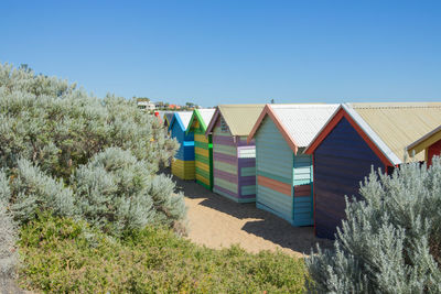 Houses on beach against clear blue sky