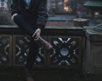 Low section of man sitting on bench at night