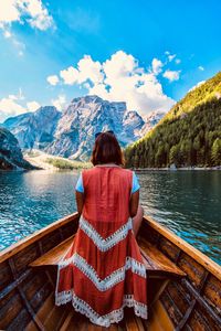 Rear view of woman sitting on canoe against mountains