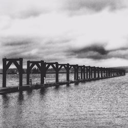 Bridge over river against cloudy sky