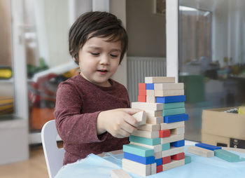 Close-up of cute boy playing with wooden blocks on table