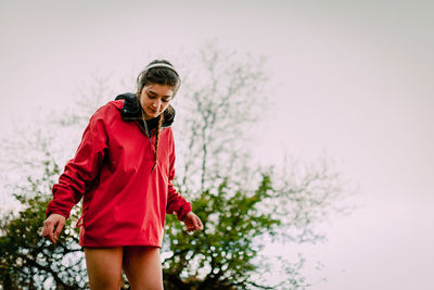 Young woman standing against sky