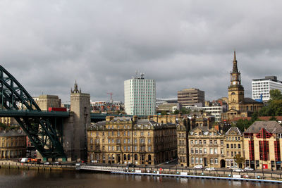 Bridge over river against buildings in city